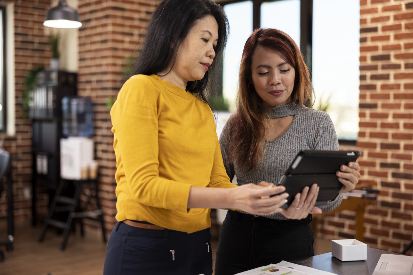 Two colleagues discussing information on a tablet