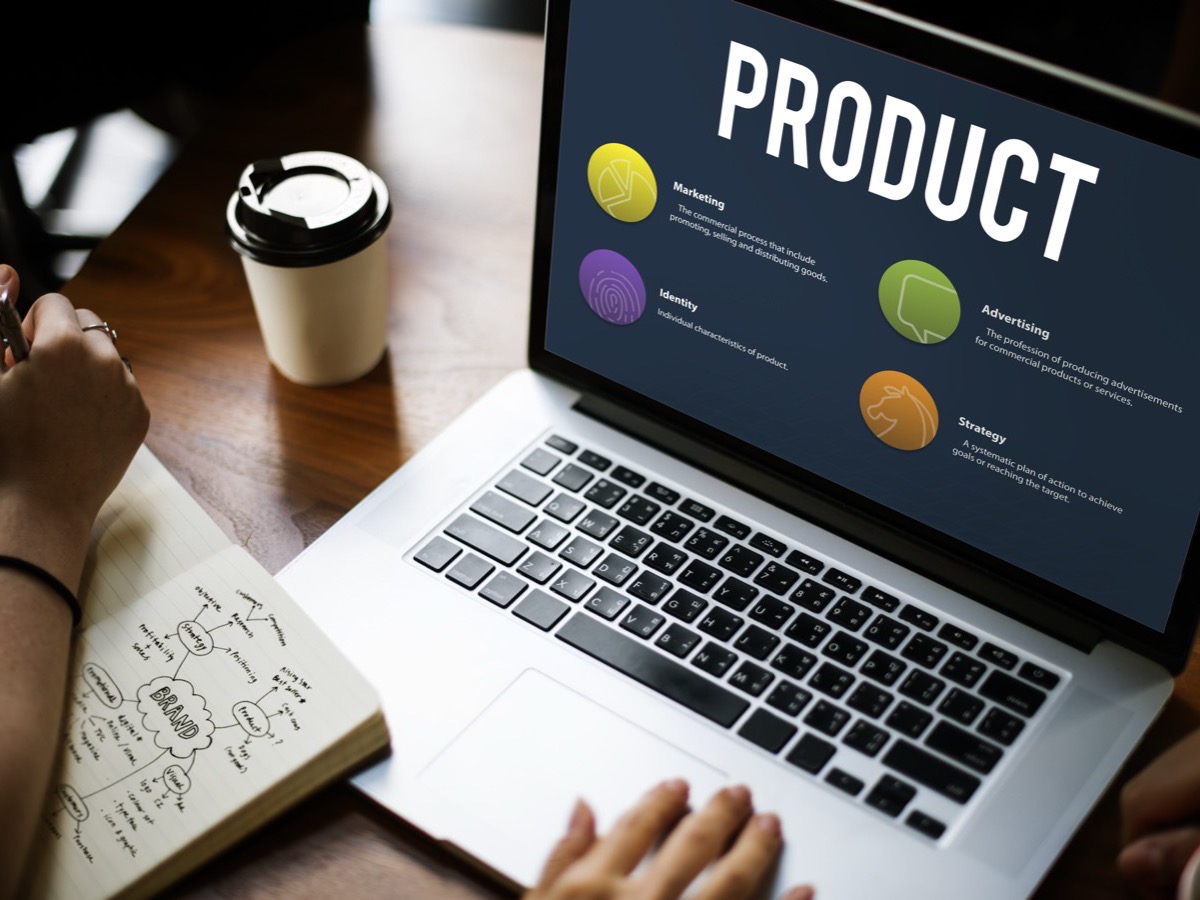 A laptop showing a product overview, next to a coffee and a notebook