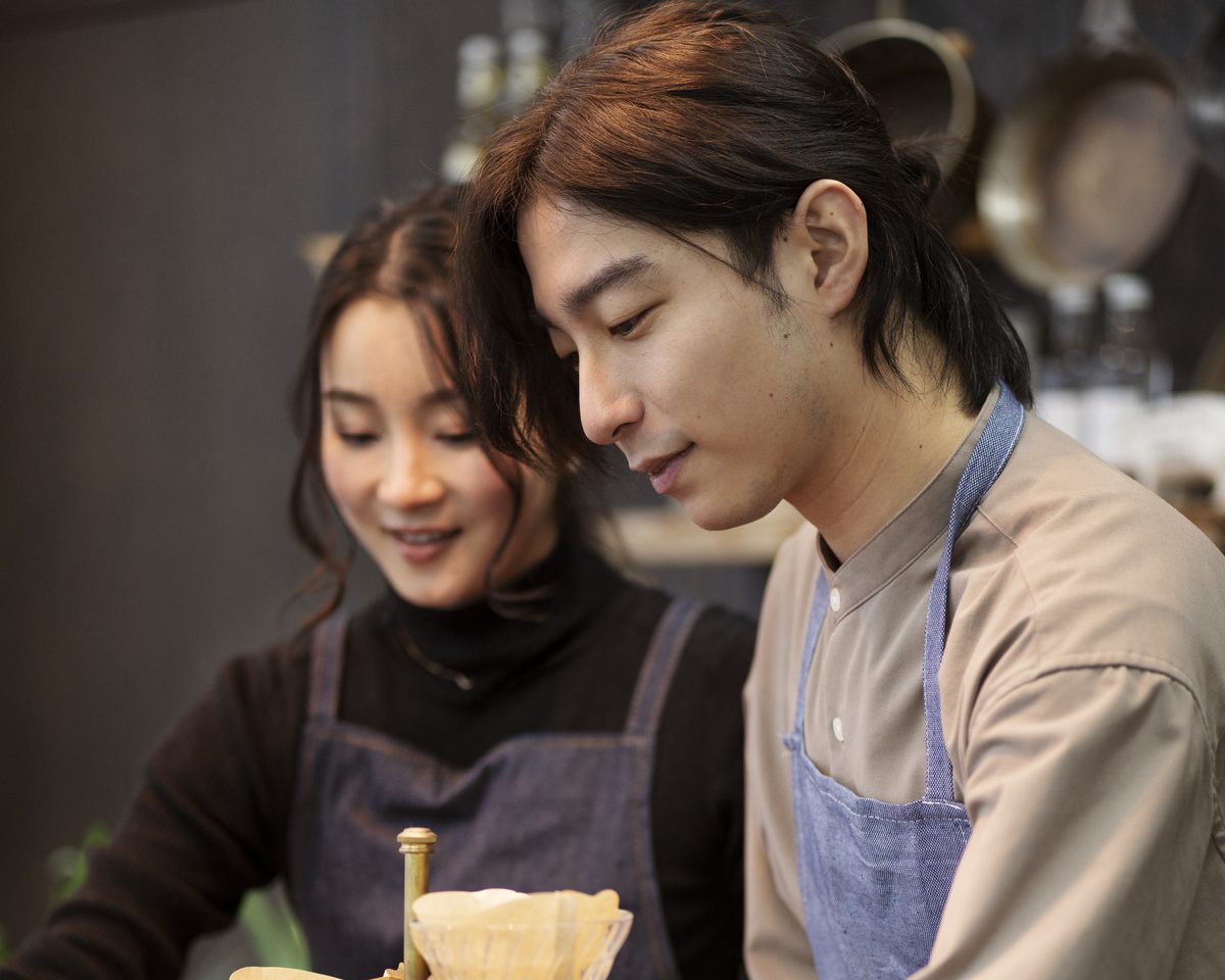 A trainer coaching a barista on the shop floor